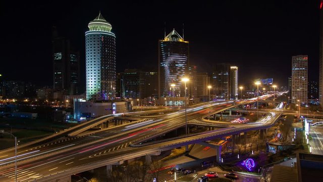 Timelapse flashing coloured Chinese advertisements on Beijing Downtown central business district buildings near huge overpass roads interchange at night