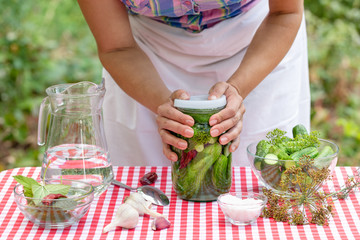 Hands of cook woman close the can with cucumbers for preservation