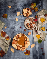 traditional pumpkin pie decorated with leaves shaped cookies on shabby blue background with coffee and textile