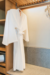 White bathrobe with wooden hangers in closet, hotel service