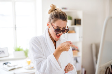 Young woman with sunglasses indoors at home in the morning, having fun.
