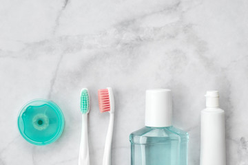 Set of pink and turquoise blue toothbrushes, toothpaste and other tools on marble background. Dental and health care concept. Top view, flat lay. Free copy space. - 303991889