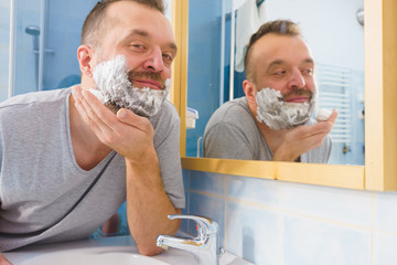 Guy shaving his beard in bathroom