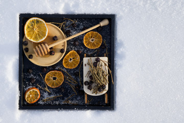 Merry Christmas and  New Year greeting card with dry orange, Clementines tangerines, honey with wooden spoon, toy sled with herbal tea and black berry on black tray