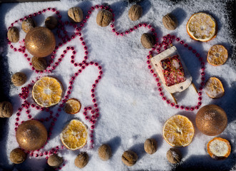 Merry Christmas and  New Year flat lay with  wooden Christmas toy sled with greeting box, gold ball, walnut  and dry orange on background