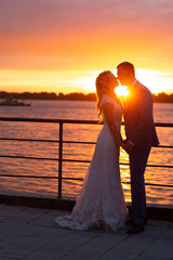 Young beautiful couple of newlyweds with bride and groom walk on the terrace by the ocean during a...