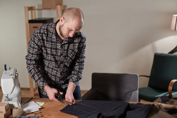 Tailor cutting wool fabric. the line pattern. Craftsman Makes rectangular blanks for Bow ties of woolen fabric. Work with sewing machine in a textile studio.