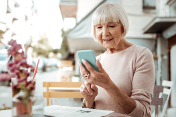 Obraz premium Nice elderly woman looking at her smartphone screen