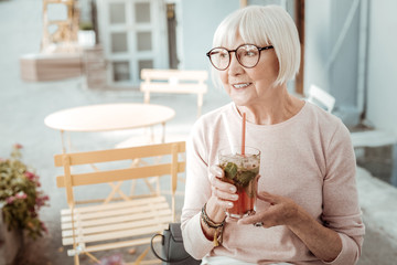 Delighted nice woman sitting with a cocktail