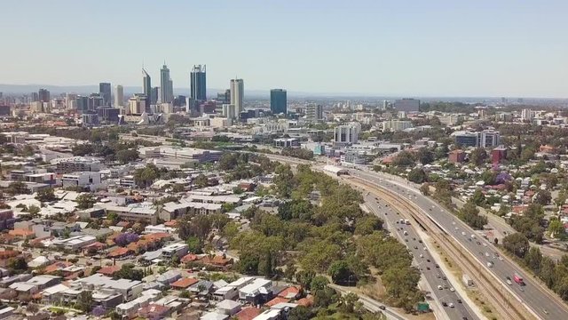 Aerial, busy freeway leading into distant highrise city. Perth, Australia.