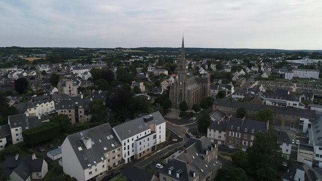 Aerial view. Catholic Gothic Cathedral in the center of the small town of Paimpol in Brittany in France. The camera moves from the spire of the temple over the roofs of traditional European houses.