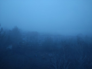 Gloomy city in the fog. Thick fog in the city. Apocalypse and post-apocalypse. Empty creepy yard...