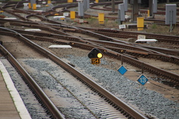 Orange sign light between railroad tracks at Amersfoort station which means speed reduction