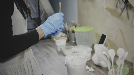 Asian master potter in blue rubber gloves dips a little clay product in a bowl with white glaze