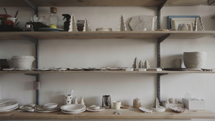 Сlay products and earthenware stand on shelves in a pottery workshop