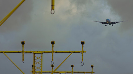 Widebody airplane with blue livery is going to land despite the strong wind. Landing lights on the...