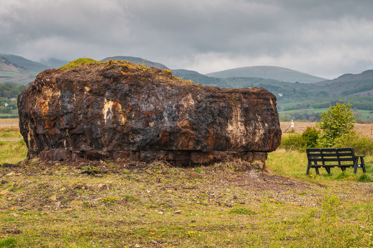 The Plug (remainder of the Ironworks), with a bench next to it and the Lake District in the background, seen at the Millom Ironworks Nature Reserve, Cumbria, England