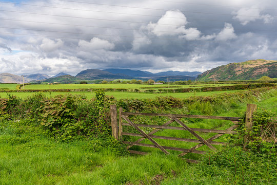A wooden gate with clouds over the Lake District National Park in the background, seen near Gubbergill, Cumbria, England, UK