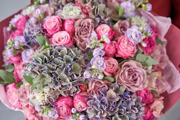 European floral shop. Beautiful bouquet of mixed flowers in womans hands. the work of the florist at a flower shop. Delivery fresh cut flower.