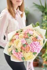 European floral shop. Beautiful bouquet of mixed flowers in womans hands. the work of the florist at a flower shop. Delivery fresh cut flower.