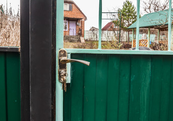 Gate with keys on a background of a country house.