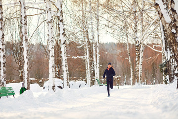 Woman running jogging in the snow in a park in winter.