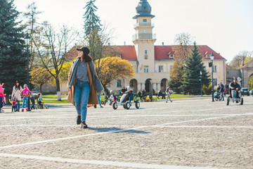 young pretty fashionable woman walking in brown coat by street