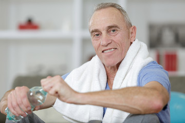 portrait of senior sportman holding water bottle indoors