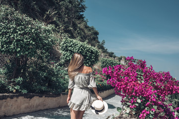 Fototapeta premium Beautiful blonde woman back view walks and admires tropical landscapes at paradise island hotel in Sanya, China. Luxury vacation banner. Tropical resort concept. Asia travel lifestyle tourist