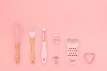 Various pink kitchen utensils on abstract pink background. Greater, whisk and iron cooking form. Top horizontal view copyspace love cookong concept