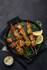 Teriyaki salmon skewers on black plate