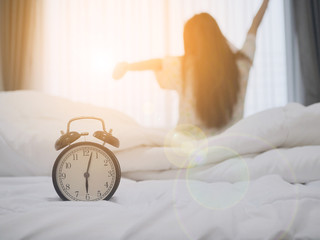 alarm clock on the bed with women wake up in the morning