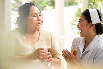 Adult female patient holding glass of water and sitting in the room.