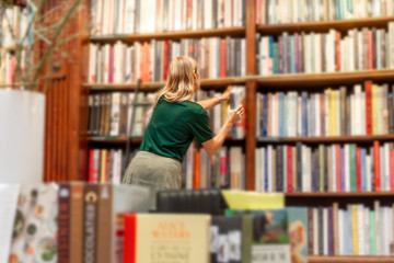 A girl is looking for a book on shelves in a large assortment store.