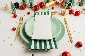 Christmas eve celebration party table setting with plates, golden cutlery, festive vintage decoration, toys over linen tablecloth background. For New Year layout.