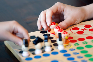 Brettspiel mit Kind , Familie, Hand und bunten Spielfiguren aus Holz.