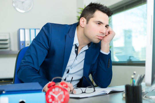 Bored Businessman Sat At Office Desk