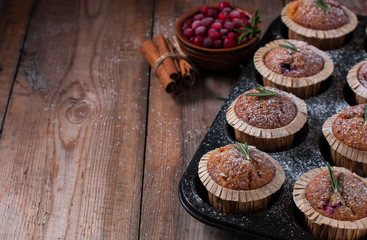 Fresh homemade Cranberry muffins in baking form on wooden table with Christmas decoration. Muffins in eco-friendly recyclable paper packaging. Selective focus, copy space.
