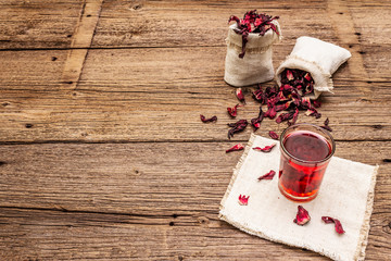 Hot hibiscus tea. Dry petals, linen sacks. Healthy food and self-care concept. Old wooden boards backgrounds