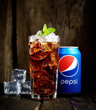 POLTAVA, UKRAINE, FEBRUARY 15, 2016  Can and glass of Pepsi-Cola with ice on wooden background. Pepsi is a carbonated soft drink sold in stores, restaurants, and vending machines throughout the world.