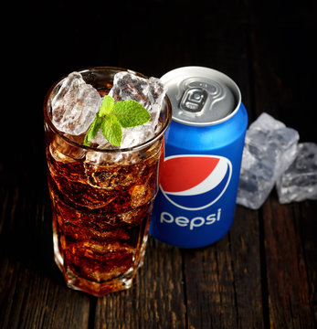 POLTAVA, UKRAINE, FEBRUARY 15, 2016  Can and glass of Pepsi-Cola with ice on wooden background. Pepsi is a carbonated soft drink sold in stores, restaurants, and vending machines throughout the world.