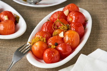 Pickled tomatoes in a white plate on a textile background