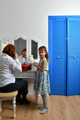 Fototapeta premium grandmother and granddaughter near cosmetic women table and red suitcase