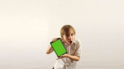 The boy holds a tablet and is surprised. His arms are hugging him from the back.