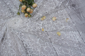 White wooden background with white spring flowers roses and lace ribbon. Happy womans day. The...
