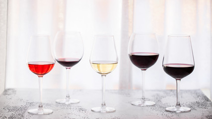 Glasses with different wine bordeaux, red, rose  and white on white background. Beautiful wine variety concept.