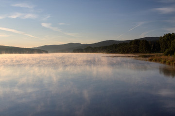 Sunrise over the lake in fog, summer morning, forest in the background, Predni Vyton, Lipno lake, Czech republic