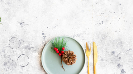 Obraz na płótnie Canvas Christmas celebration background. Green plate fir tree brunch and golden cutlery. Winter holidays and festive dinner concept. Copy space.