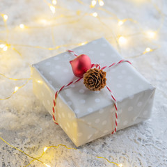 Christmas festive background with present box and glowing garland on the snow. Greeting festive image.