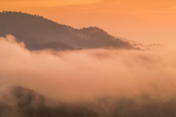 Mountain view misty morning of the mist moving on top hill above Tha Ton city with yellow sun light in the sky background, sunrise at Wat Tha Ton, Chiang Mai, Thailand.